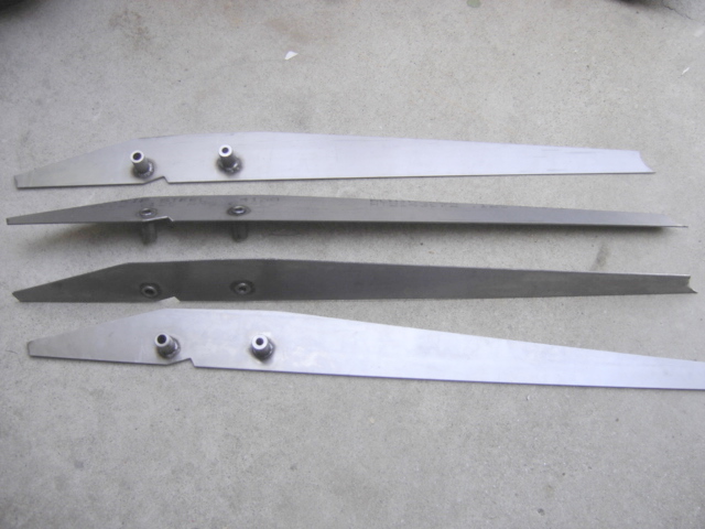 Four custom metal blades with bolts on a concrete surface