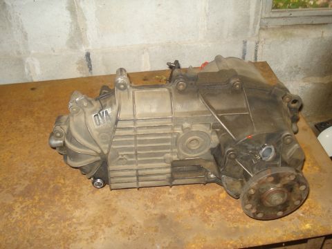 1991 Ford Bronco - A dusty transfer case, possibly from a 1991 Ford Bronco, rests on a rusty metal surface. The transfer case is made of aluminum and has the…