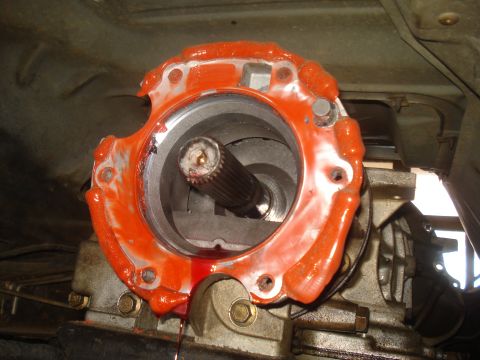 1991 Ford Bronco - A close-up view of a vehicle's transfer case with orange sealant applied to the mating surface. A splined shaft is visible protruding from…