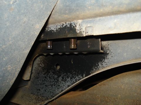1991 Ford Bronco - Two bolts are visible on a black metal bracket attached to the underside of a vehicle. Oily residue is present on the bracket and surroundi…