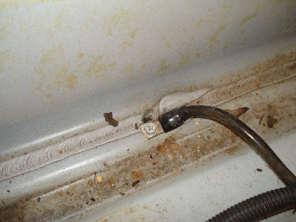 Ground strap bolted to a metal surface with weld seam, and a black wire.