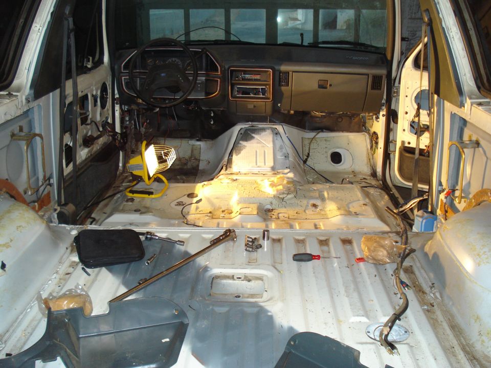 Interior of a disassembled 1991 Ford Bronco with bare metal floor, dashboard, and steering wheel.
