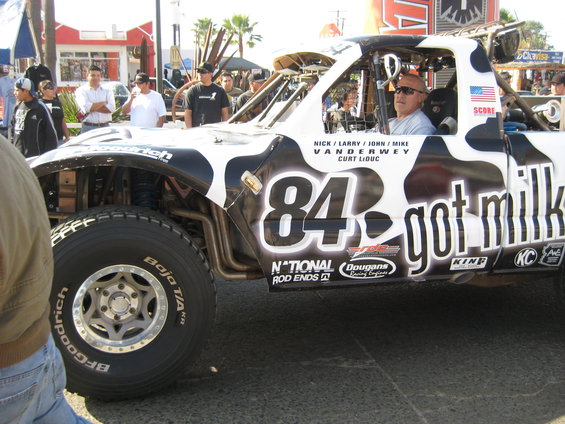 Off-road truck with cow print wrap and number 84, parked outdoors.