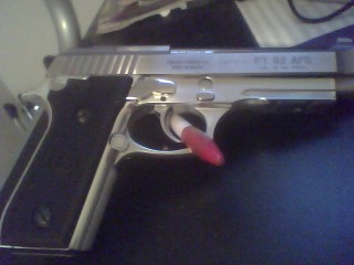 1990 Ford Bronco - A silver pistol with black grips is shown with a red marker in the trigger guard.
