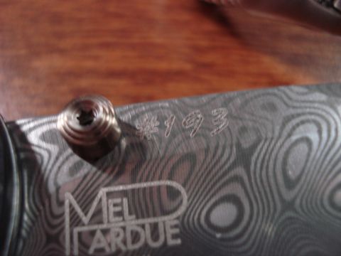 2000 Ford Crown Victoria - Close-up of a knife handle showing the Damascus pattern and engraved maker's mark and serial number.