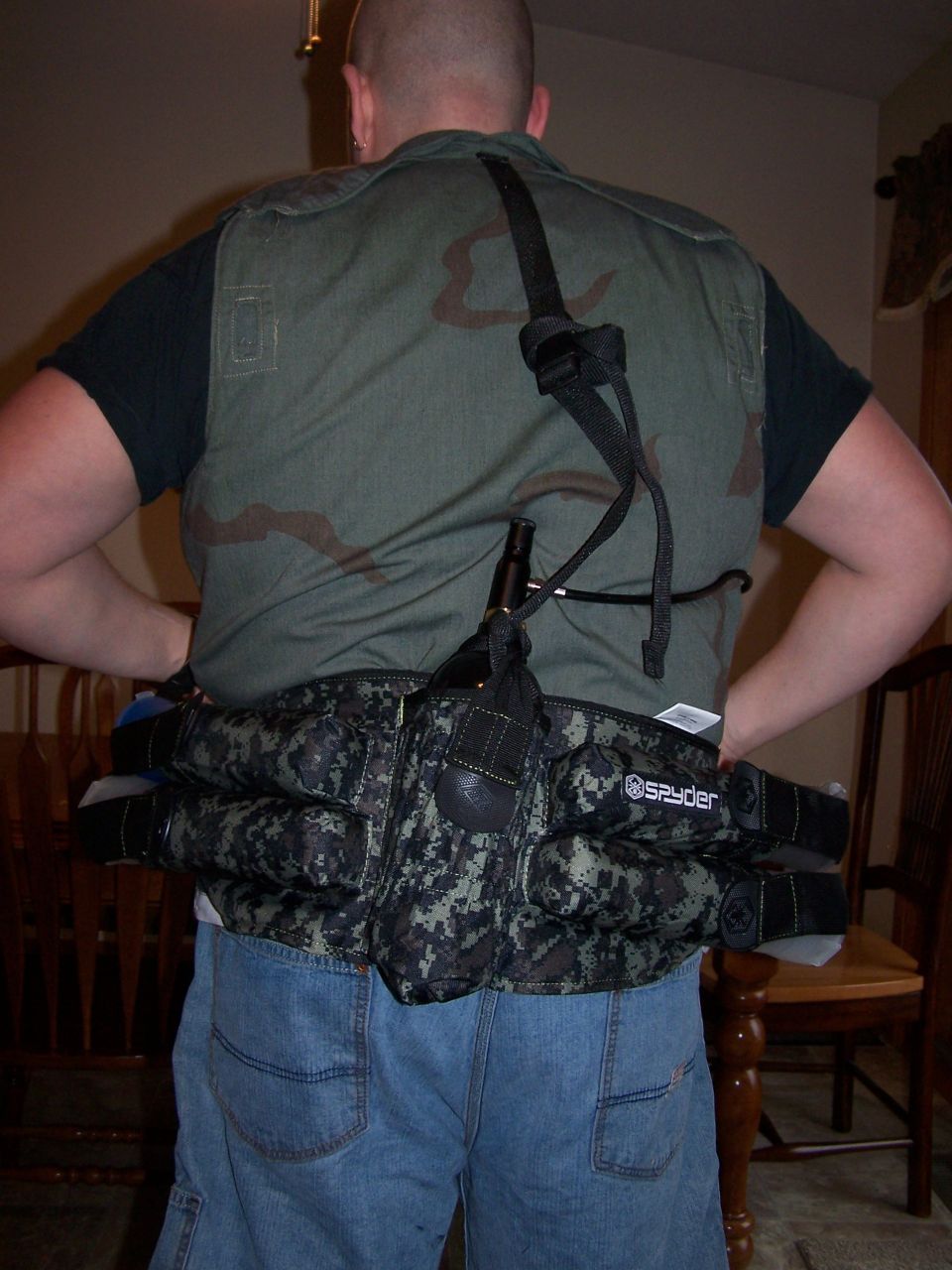 Person from behind wearing a camo vest and a large camo utility belt with a bottle attached