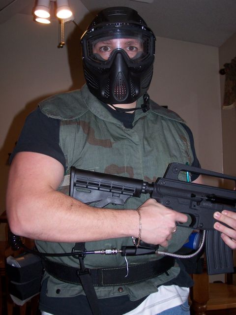 1986 Ford Bronco - A person wearing a black paintball mask and helmet, a camouflage vest, and holding a paintball gun.