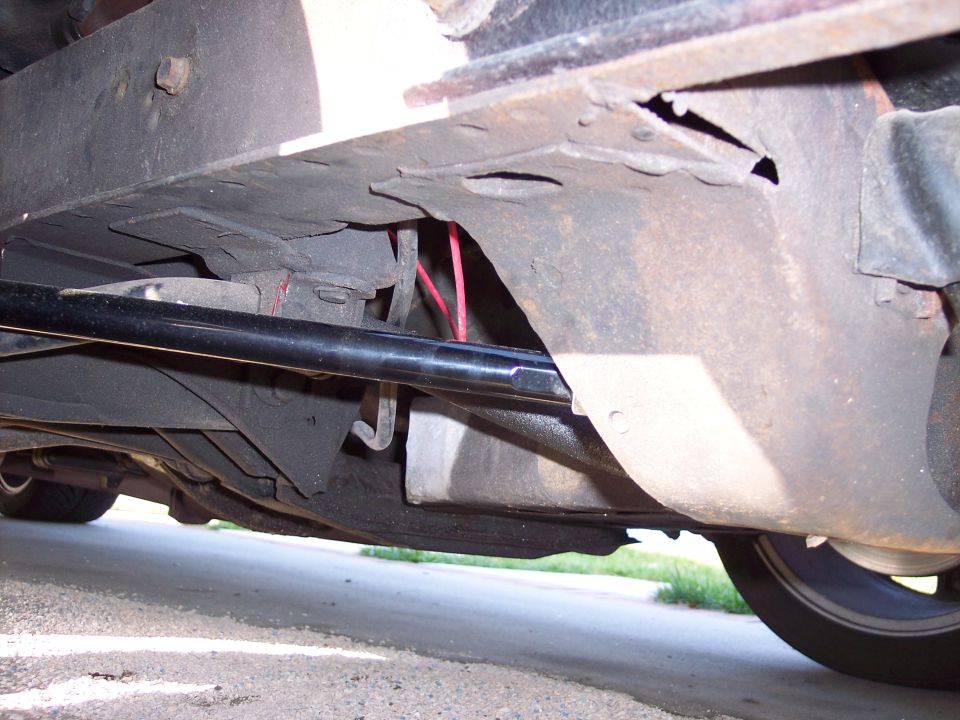 Underside of a classic car showing suspension components and red wires.