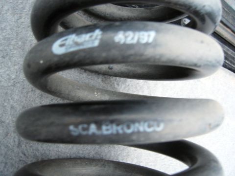 1986 Ford Bronco - A close-up, slightly angled shot shows a black Eibach suspension coil spring with white lettering. The visible text includes "Eibach 42/97"…