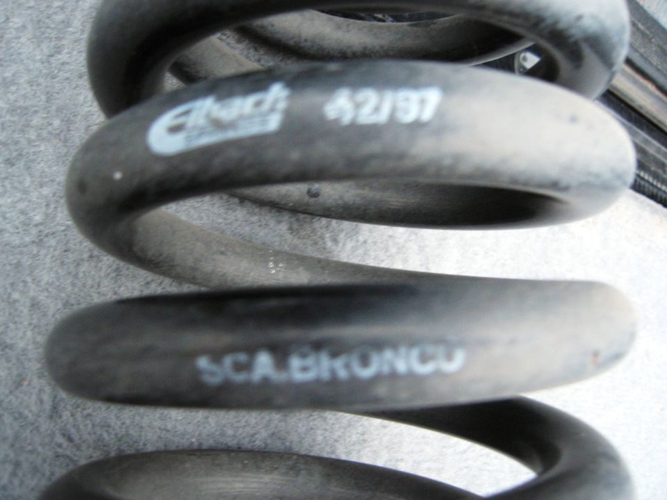 Black Eibach suspension coil spring with white lettering: "Eibach 42/97" and "SCA.BRONCO".