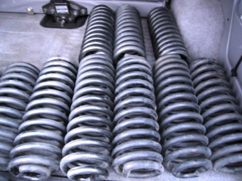 1986 Ford Bronco - Several sets of silver coil springs are neatly arranged in rows inside what appears to be the cargo area of a vehicle. A black metal object…