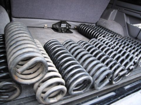 1986 Ford Bronco - Several sets of aftermarket coil springs are laid out in the cargo area of a vehicle. The springs vary in color from dark gray to black and…
