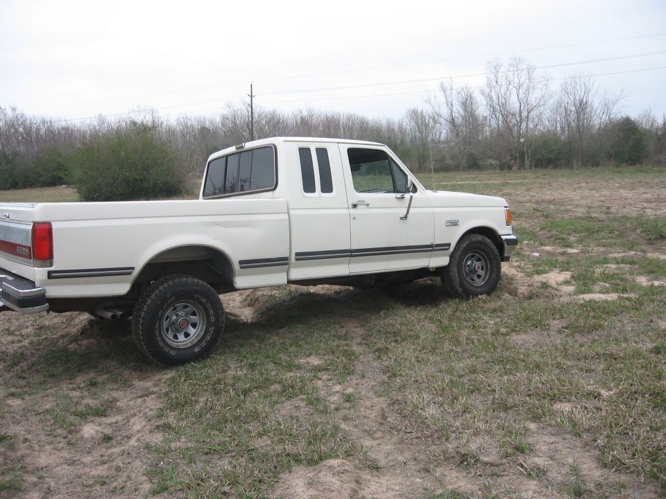 White 1990 Ford F-150 pickup truck parked on a dirt lot.