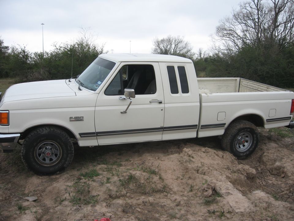 White 1990 Ford F-150 extended cab pickup truck parked on dirt.