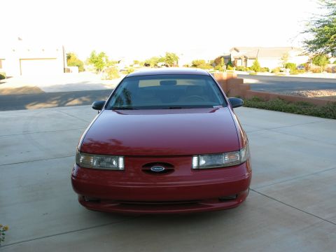 1995 Ford Taurus - Front view of a red 1995 Ford Taurus sedan parked in a driveway.
