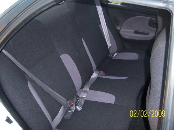 Black and gray rear bench seat of a compact car with belts buckled