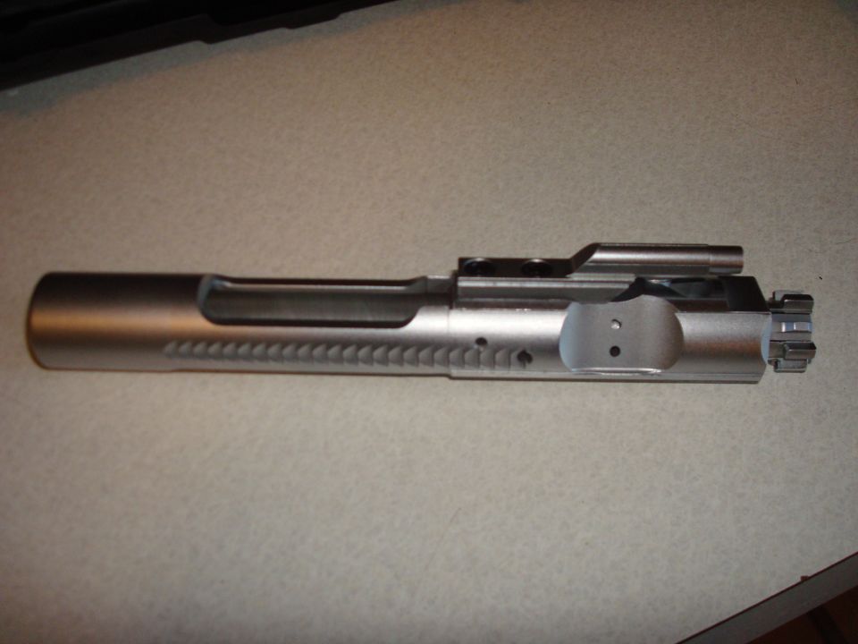 Silver AR-15 bolt carrier group on a speckled surface