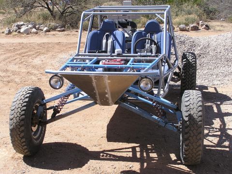 1993 Ford Taurus - Front view of a custom-built dune buggy with a blue interior and a silver metal front skid plate. The vehicle is parked on a dirt surface w…