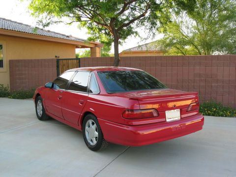 1995 Ford Taurus - Rear 3/4 view of a red 1995 Ford Taurus sedan parked in a driveway.