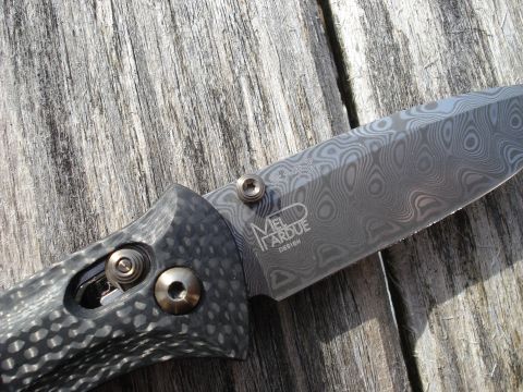 2000 Ford Crown Victoria - A close-up shot of a folding knife with a Damascus steel blade and a carbon fiber handle resting on a weathered wooden surface.