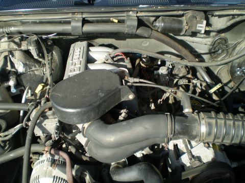 1996 Ford Bronco - The image shows a close-up view of a Ford Bronco engine bay, focusing on the intake system and valve cover. Various hoses, wires, and engin…