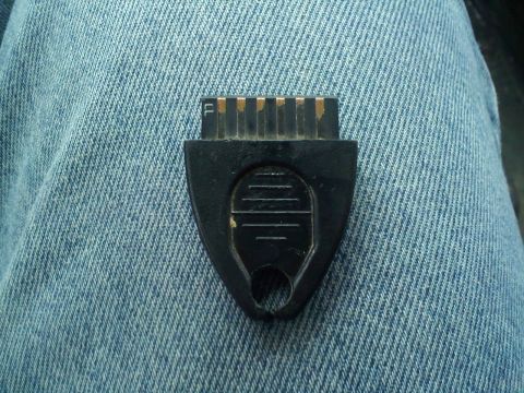 1994 Ford Bronco - A black electronic diagnostic connector with gold-colored pins is shown resting on blue denim fabric.