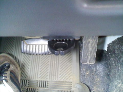 1994 Ford Bronco - A close-up view of the driver's side footwell of a vehicle, showing the brake and accelerator pedals, along with a portion of a shoe. The p…