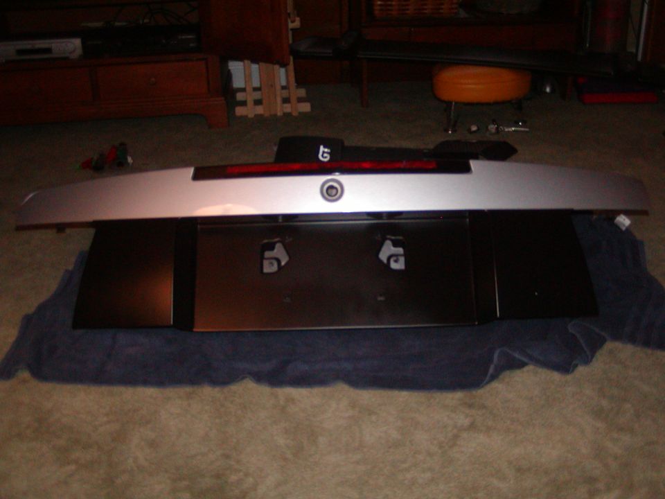 Silver rear spoiler with red brake light mounted on black license plate bracket