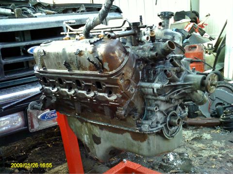 1992 Ford Bronco - A heavily used and dirty V8 engine is mounted on a red engine stand in an outdoor setting. The engine appears to be from a Ford vehicle, as…