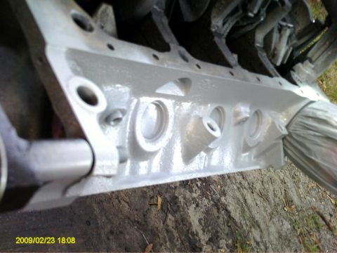 1992 Ford Bronco - A close-up view of a gray-painted engine block with visible bolt holes and internal cylindrical structures. A silver metal tube extends fro…