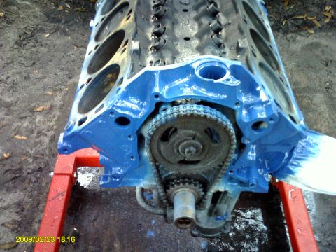 1992 Ford Bronco - A blue-painted engine block is mounted on a red engine stand. The timing chain and gears are visible at the front of the engine.
