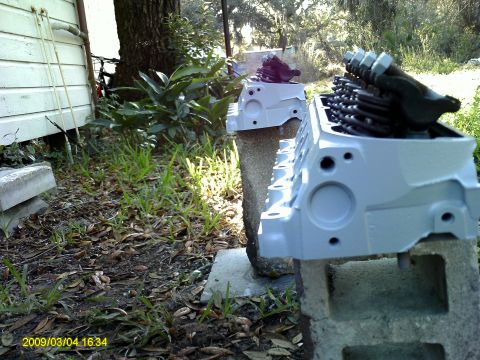 1992 Ford Bronco - Two light blue painted engine blocks with visible valve train components are displayed outdoors on cinder blocks. The engine block in the f…