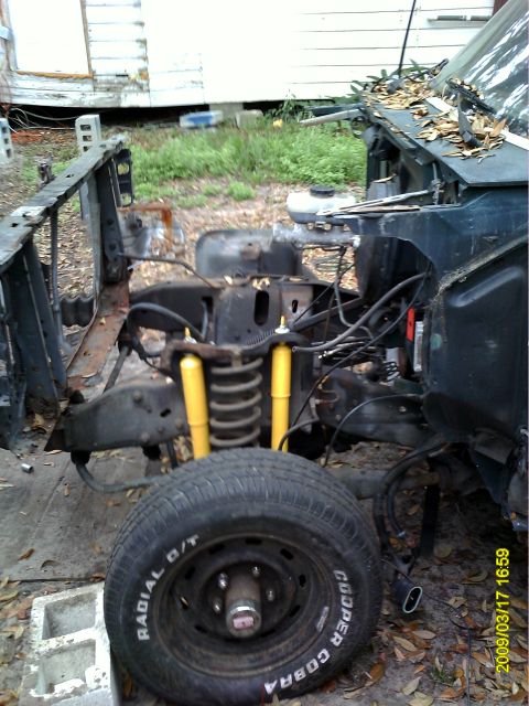 1992 Ford Bronco - The front end of a disassembled vehicle, likely a truck or SUV, is shown with the engine bay exposed. A large tire with "Cooper Cobra" text…