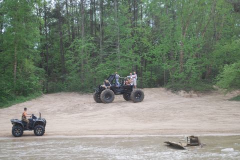 2008 Jeep Wrangler - Two off-road vehicles are on a sandy track with a wooded area in the background. A person rides an ATV in the foreground, while a larger bu…