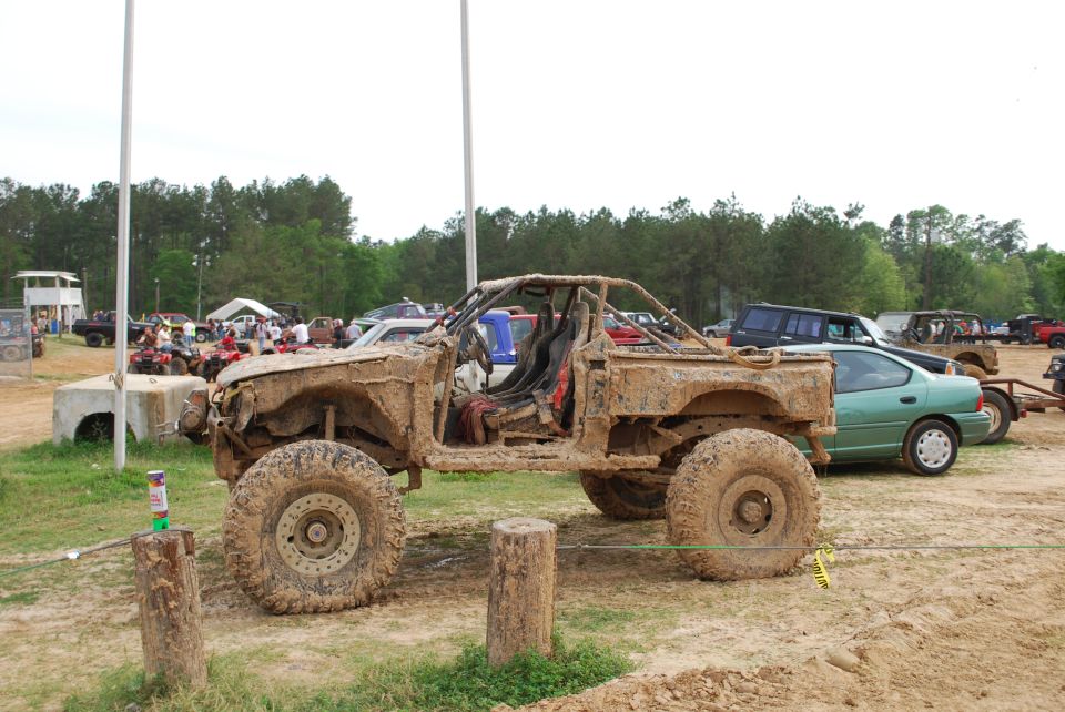 Mud-covered off-road Jeep with roll cage and exposed interior.