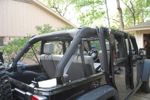 2008 Jeep Wrangler - The interior and side of a black Jeep Wrangler is shown with the doors and top removed. The rear seats and roll cage are visible.
