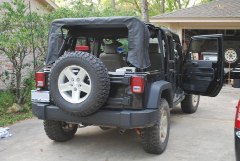 2008 Jeep Wrangler - The rear driver's side of a black Jeep Wrangler is shown parked in a driveway with the soft top partially deployed and the driver's door op…