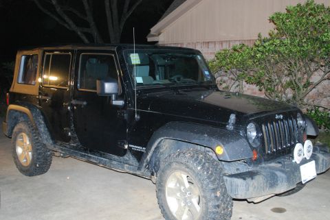 2008 Jeep Wrangler - A black 2008 Jeep Wrangler Unlimited is parked on a concrete surface at night, with a house and trees in the background. The vehicle has of…