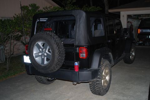 2008 Jeep Wrangler - The rear driver's side of a black Jeep Wrangler is shown parked on a concrete driveway at night. The vehicle has a soft top, a spare tire m…