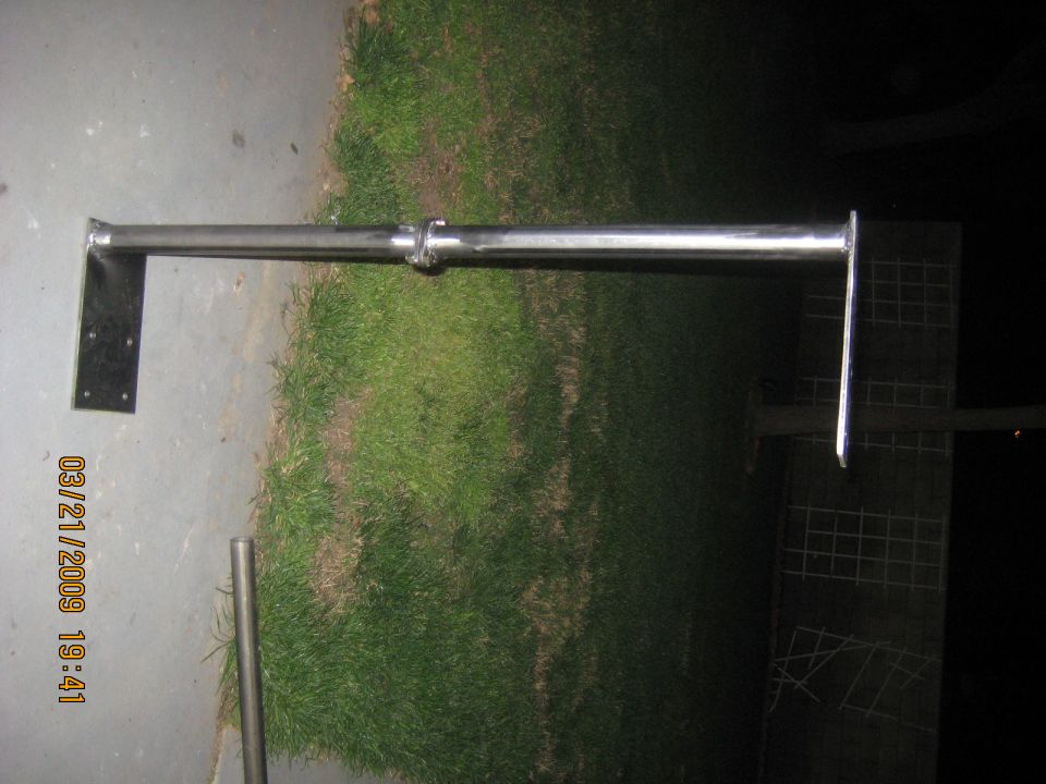 Metal bracket assembly with mounting plates on concrete and grass.
