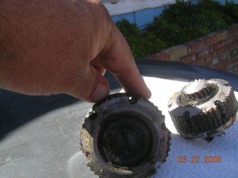 1985 Ford Bronco - A hand holds a dirty, used auto part next to another identical part, with a date stamp visible.