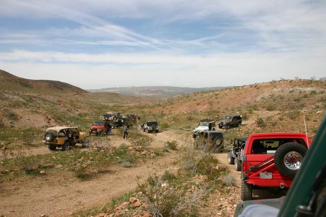 Multiple off-road vehicles on a dirt path in a desert canyon