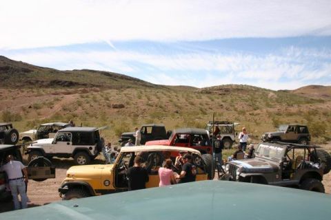 1991 Ford Bronco - A group of off-road vehicles are gathered in a dry, hilly area under a partly cloudy sky.