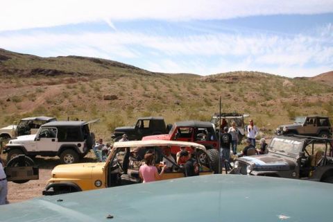 1991 Ford Bronco - A group of Jeeps are gathered in a desert area under a partly cloudy sky.