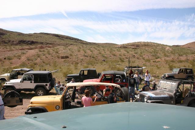 Several Jeep SUVs parked in a desert landscape with people standing around