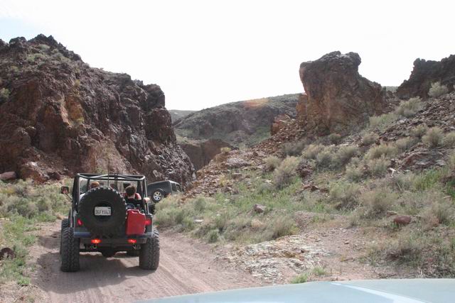 Rear view of Jeep Wrangler with spare tire and red gas can on off-road trail