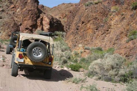 1991 Ford Bronco - Two Jeep Wranglers navigate a rocky, desert terrain on a sunny day.
