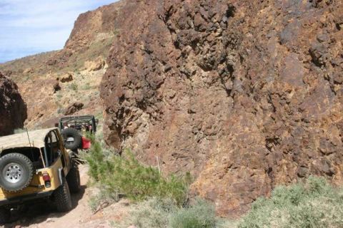 1991 Ford Bronco - Off-road vehicles navigate a challenging trail in a , rocky landscape.