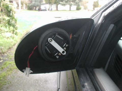 1990 Ford Thunderbird - The internal components of a car's side mirror are visible, showing wiring and adjustment mechanisms.