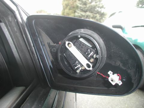 1990 Ford Thunderbird - Close-up view of the internal components and wiring of a disassembled side mirror assembly.